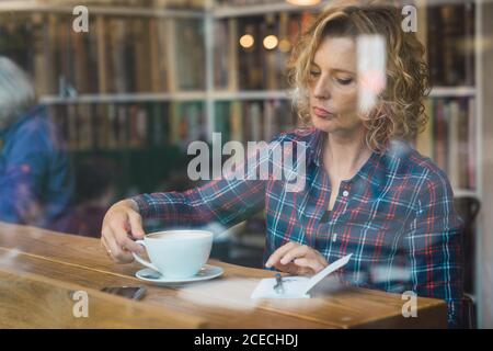 Woman sitting in cafe and writing in notebook Stock Photo