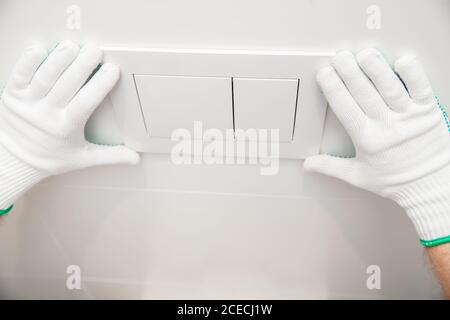 Plumber installing toilet bowl in restroom, work in bathroom Stock Photo