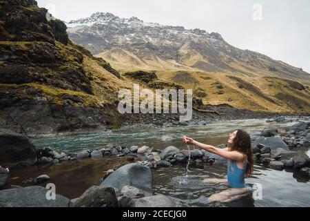 Young Woman sitting in mountain river Stock Photo