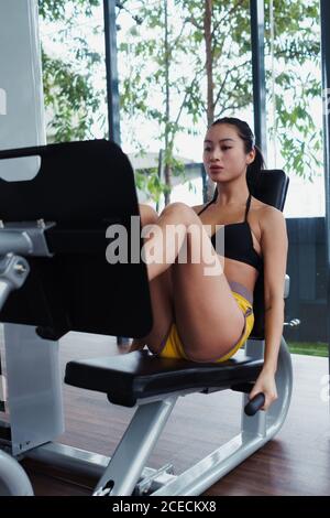 Pretty Asian Woman pushing machine and exercising in the gym. Stock Photo