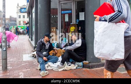 Men sat in doorway of closed down STA travel shop on corner of Ship Street and North Street Brighton with dog UK