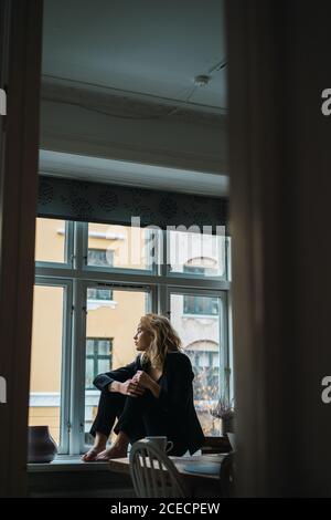 Romantic Woman posing on windowsill Stock Photo