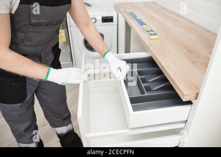 Kitchen installation man. Worker assembling furniture cabinet hinge Stock Photo