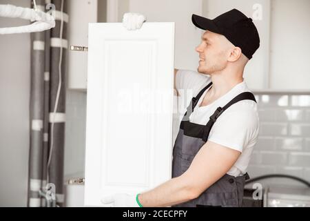 Kitchen installation man. Worker assembling furniture cabinet hinge Stock Photo