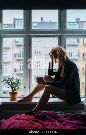 Romantic Woman posing on windowsill Stock Photo