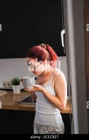 Woman drinking coffee in kitchen Stock Photo