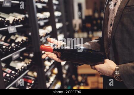 Bartender sommelier takes bottle of red wine from counter of restaurant drinks store Stock Photo