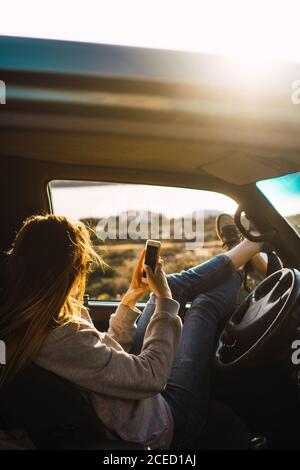 Woman with smartphone in car in nature Stock Photo