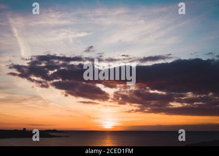 View to orange sunset in cloudy sky over the ocean. Stock Photo