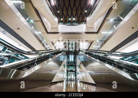 Two escalators located in brightly lit hall of modern mall in Singapore Stock Photo