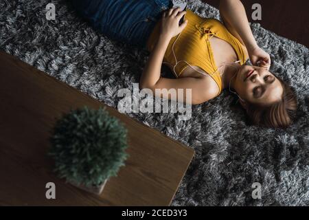 Woman with earphones lying on floor Stock Photo