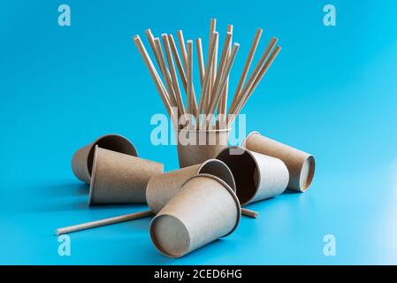 Disposable brown craft paper cups with paper straws on blue background. Eco-friendly tableware. Go green concept. Zero waste theme Stock Photo
