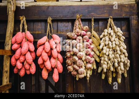 Bunches of traditional harvested Chinese garlic, peanuts and other root vegetables hanging on old weathered wooden plank wall in province of Guangxi in China Stock Photo