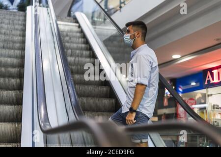 Closeup shot of a young man wearing a medical mask going up on an escalator Stock Photo