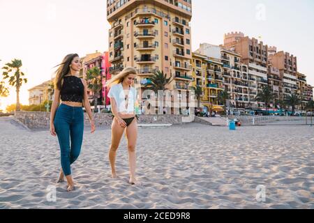 Beautiful female friends walking on beach Stock Photo