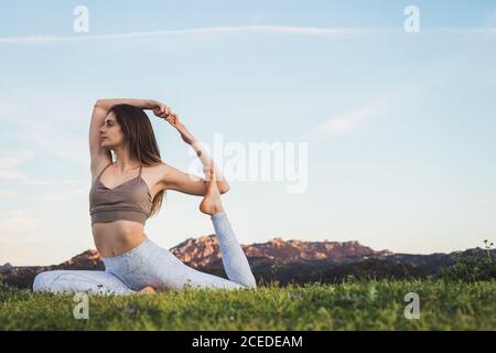 Woman stretching and doing yoga on field Stock Photo