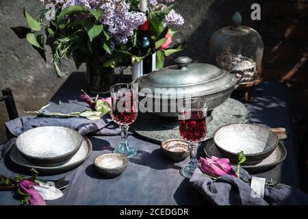 Tablecloth setting with artichokes, flowers and red wine Stock Photo