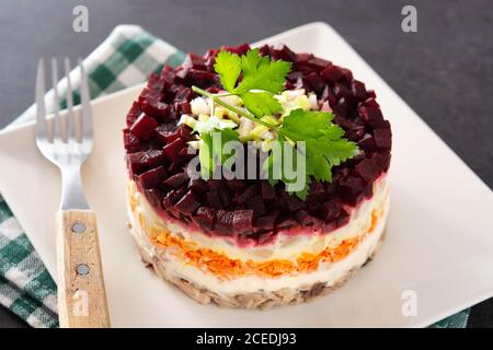 Traditional Russian herring salad with beetroot and carrots on black background Stock Photo