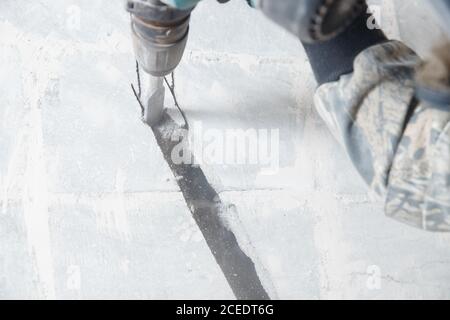 Builder worker man using jackhammer to drill into construction wall for duct for air conditioning pipes Stock Photo