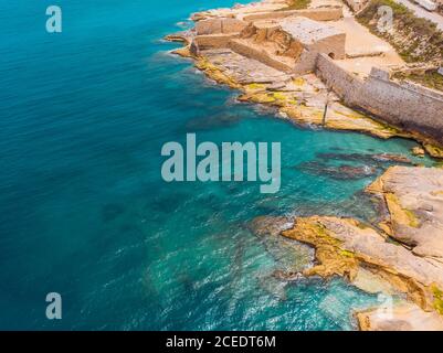 Ancient stone military fort Malta island made of brick rocks on shore blue sea with view city Valetta, aerial top view Stock Photo