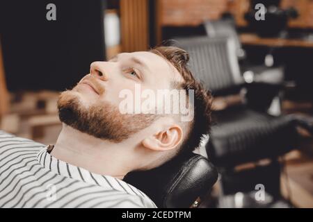 Man sits in chair in barbershop preparing to cut Stock Photo