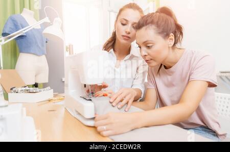 Teacher woman helping students girl sews clothes college, studying fashion and design Stock Photo