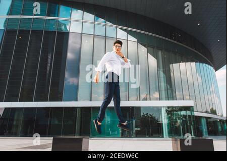 man jumping on pavement of highrise Stock Photo