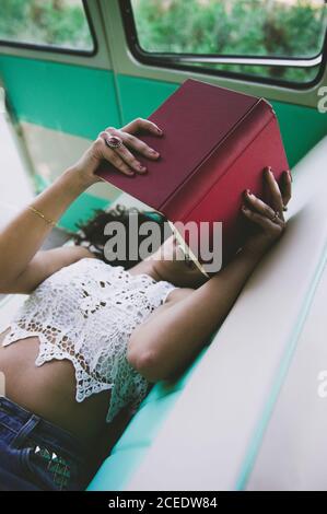 Woman lying inside a caravan and reading a book Stock Photo