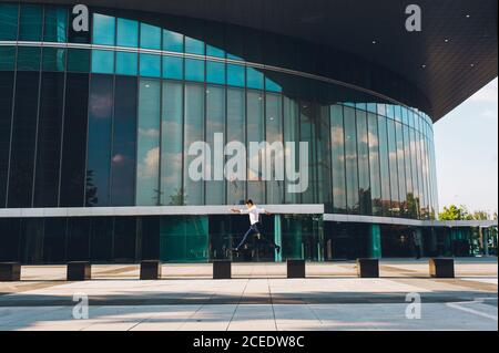 man jumping on pavement of highrise Stock Photo