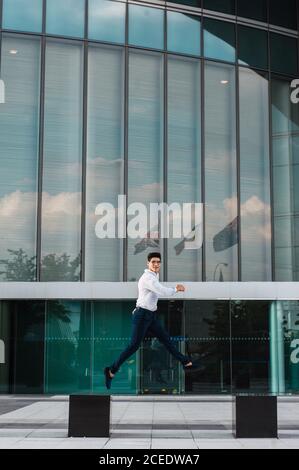man jumping on pavement of highrise Stock Photo