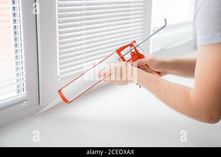 Construction worker use gun silicone tube for repairing and installing window in house Stock Photo