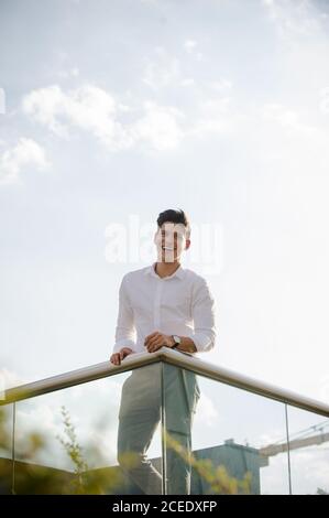 Young man leaning on railing Stock Photo
