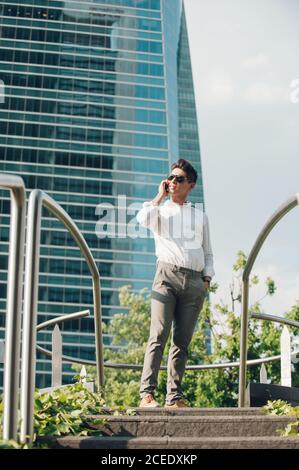 Cheerful man with smartphone walking down steps Stock Photo