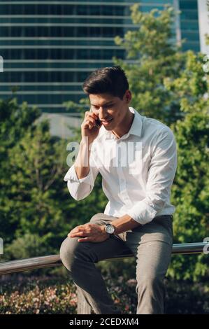 Young man talking phone on railing Stock Photo