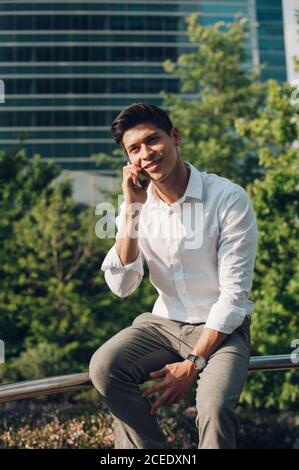 Young man talking phone on railing Stock Photo