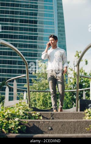 Cheerful man with smartphone walking down steps Stock Photo