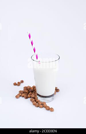 Heap of tasty raisins lying near glass with fresh milk and striped straw on white background Stock Photo