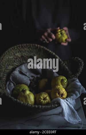 Crop Woman peeling exotic fruit over basket Stock Photo