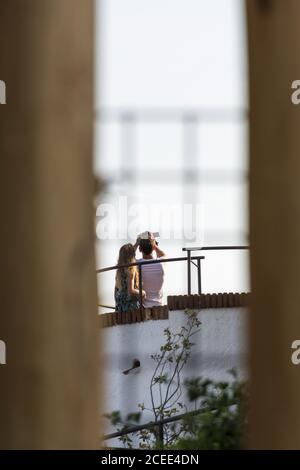 Back view of unrecognizable couple standing on roof and taking selfie with photo camera Stock Photo