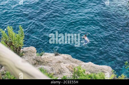From above unrecognizable man in snorkeling mask swimming in blue ocean Stock Photo