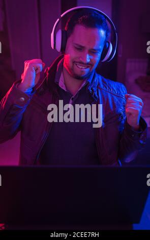 Latin man listening cheerfully to music with headphones on his laptop Stock Photo