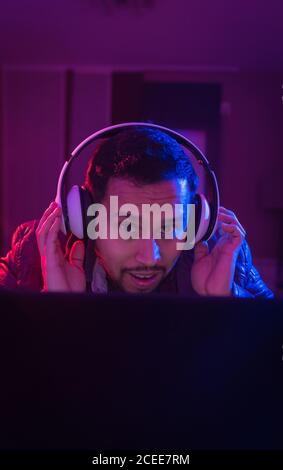 Latin man listening cheerfully to music with headphones on his laptop Stock Photo