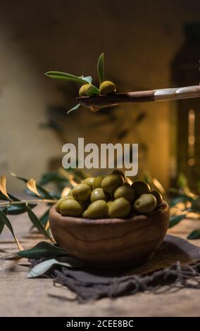 Virgin olive oil falling on a bowl full of green olives Stock Photo