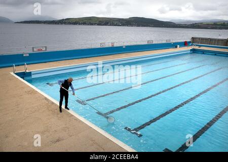 Jim Lyon facilities manager at Inverclyde Leisure sweeps the outdoor swimming pool in Gourock as it refills with water ahead of re-opening this Monday as Scotland continues to come out of lockdown Stock Photo