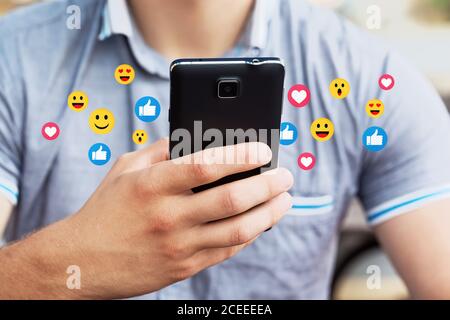 Man using mobile smart phone, close up. Picture of young man using a mobile smart phone and smiling. Stock Photo