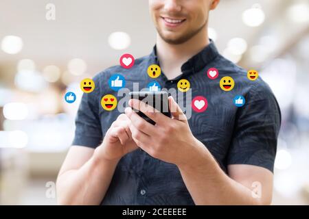Man using mobile smart phone, close up. Picture of young man using a mobile smart phone and smiling. Stock Photo