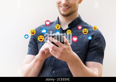 Man using mobile smart phone, close up. Picture of young man using a mobile smart phone and smiling. Stock Photo