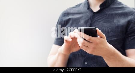 Man using his mobile phone outdoor, close up. Man holding mobile smart phone with blurred background. Stock Photo