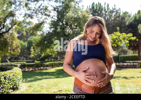 Smiling pregnant attractive Woman in park Stock Photo