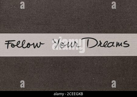 White and Grey coloured paper background with Follow Your Dreams motivational handwritten message Stock Photo